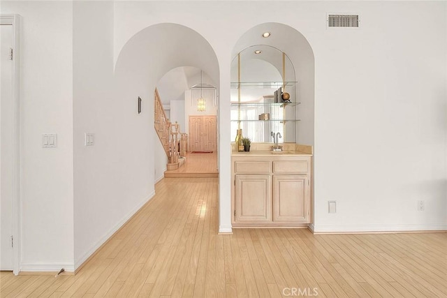 17527 Mondino Dr, Rowland Heights, CA 91748 - hallway featuring a sink, light wood finished floors, stairway, baseboards, and arched walkways