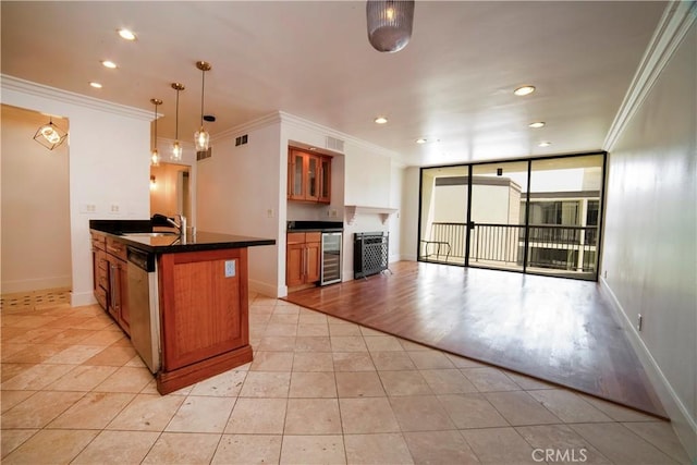 kitchen with brown cabinetry, a sink, dark countertops, and ornamental molding
