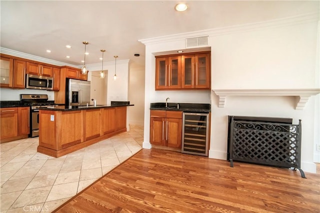 kitchen featuring brown cabinets, stainless steel appliances, wine cooler, visible vents, and ornamental molding