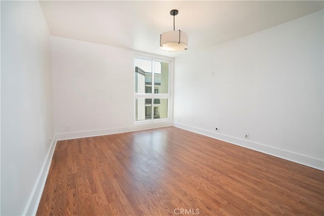 unfurnished room with baseboards and wood finished floors