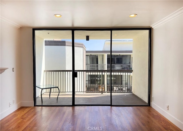 empty room with crown molding, baseboards, expansive windows, and wood finished floors