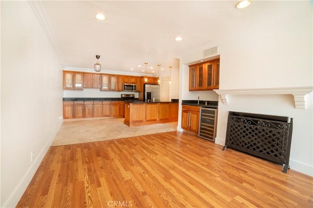 unfurnished living room with wine cooler, crown molding, light wood finished floors, and visible vents