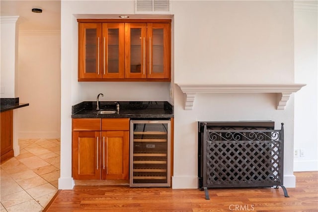 bar with wet bar, visible vents, a sink, baseboards, and beverage cooler