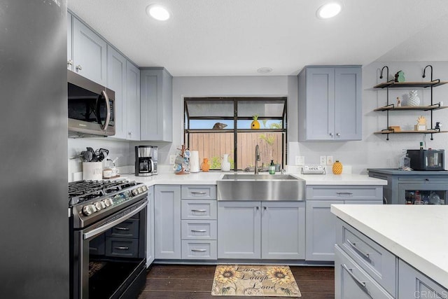 kitchen with a sink, appliances with stainless steel finishes, dark wood-style floors, and light countertops