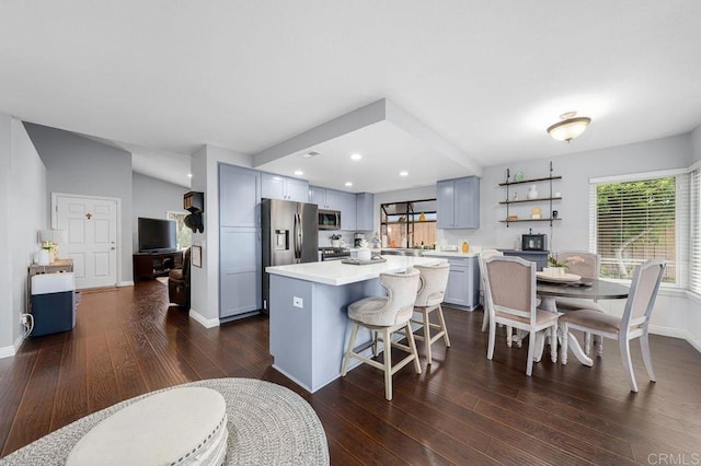 kitchen featuring a kitchen bar, a center island, light countertops, dark wood-style floors, and stainless steel appliances