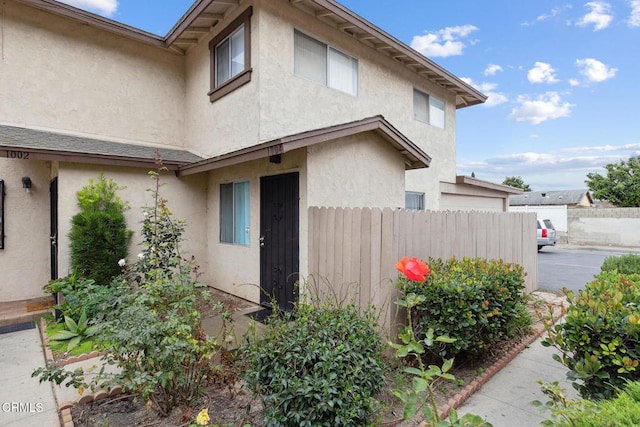 view of side of property featuring fence and stucco siding