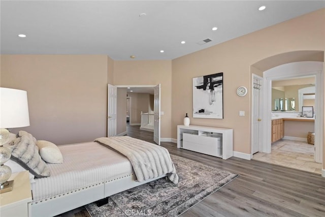 bedroom with visible vents, arched walkways, baseboards, light wood-style floors, and recessed lighting