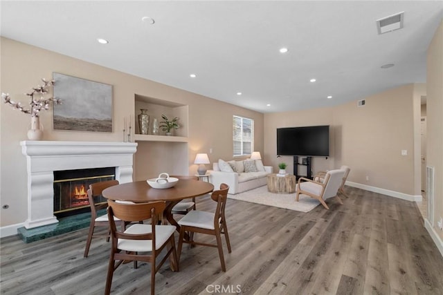 dining room with a glass covered fireplace, baseboards, recessed lighting, and wood finished floors