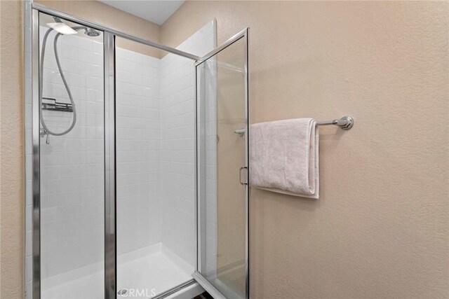 full bath featuring a textured wall and a stall shower