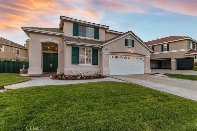 traditional-style house with fence, stucco siding, a tiled roof, a lawn, and driveway