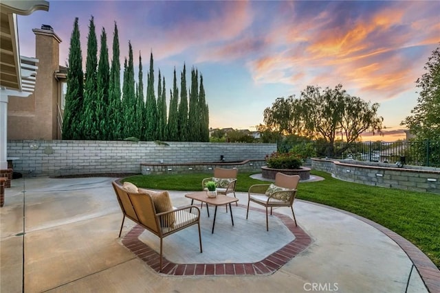 patio terrace at dusk with a fenced backyard and a yard