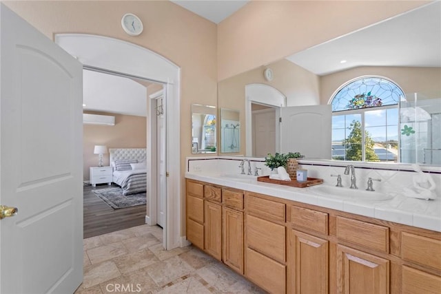 ensuite bathroom with double vanity, a wall mounted AC, a sink, and ensuite bath