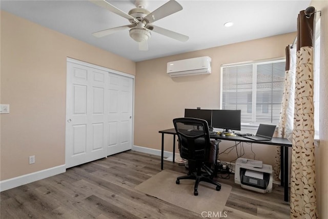 office space featuring baseboards, a wall mounted AC, a ceiling fan, and wood finished floors