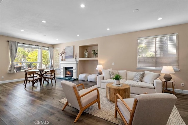 living area with baseboards, recessed lighting, a glass covered fireplace, and wood finished floors