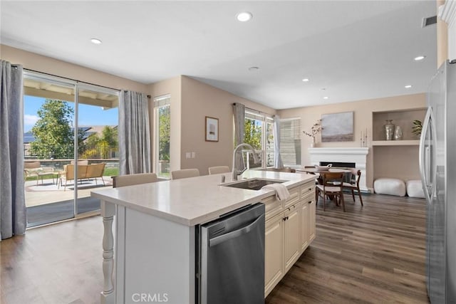 kitchen with visible vents, a kitchen island with sink, a fireplace, a sink, and appliances with stainless steel finishes