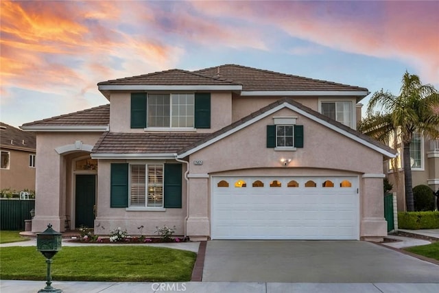 traditional home featuring an attached garage, a front lawn, stucco siding, and driveway