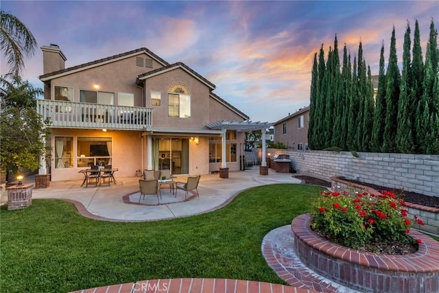 back of property at dusk with a patio, a yard, stucco siding, and a pergola