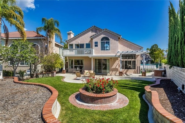 back of property with a patio, a yard, stucco siding, and a balcony