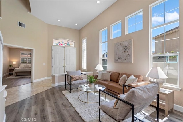 living area with a towering ceiling, a wealth of natural light, wood finished floors, and visible vents