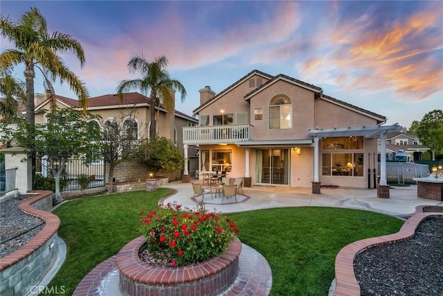 back of property with a patio, a yard, and a balcony