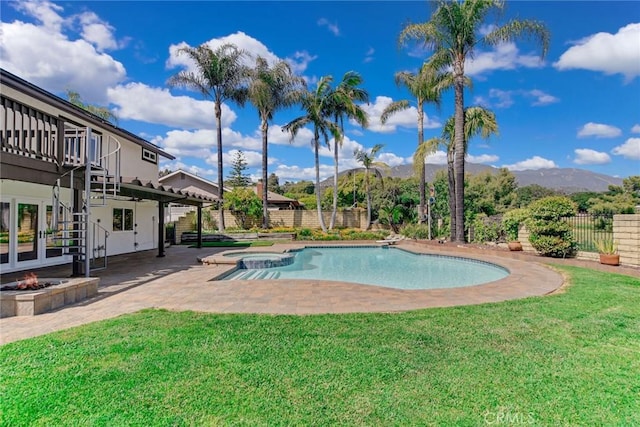 view of swimming pool featuring a patio, a fenced backyard, a lawn, a mountain view, and a pool with connected hot tub