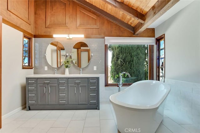 bathroom with a sink, vaulted ceiling with beams, a soaking tub, and a wealth of natural light
