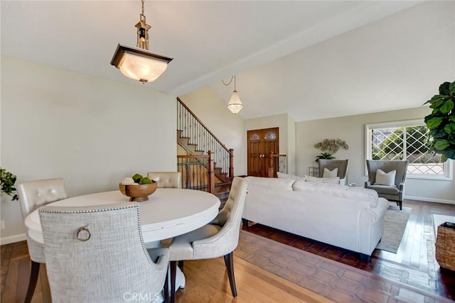 dining area featuring baseboards, vaulted ceiling, wood finished floors, and stairway