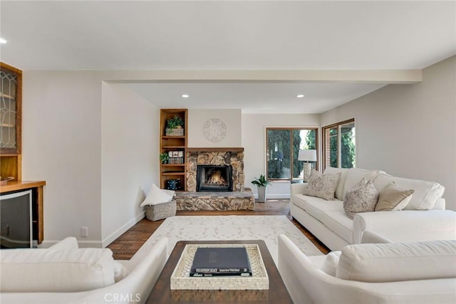 living area featuring baseboards, a stone fireplace, recessed lighting, and wood finished floors