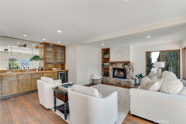 living room featuring a fireplace, wood finished floors, beverage cooler, indoor bar, and recessed lighting