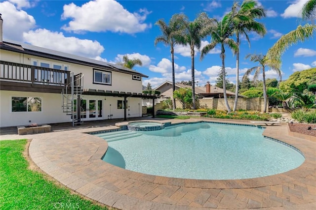 view of swimming pool featuring a wooden deck, a patio, a fenced backyard, a pool with connected hot tub, and stairway