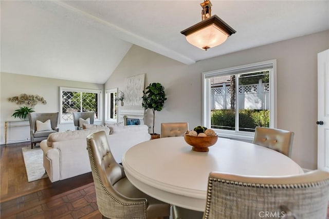 dining area with a glass covered fireplace and vaulted ceiling