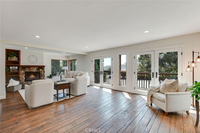 living area featuring french doors, recessed lighting, a fireplace, and hardwood / wood-style flooring