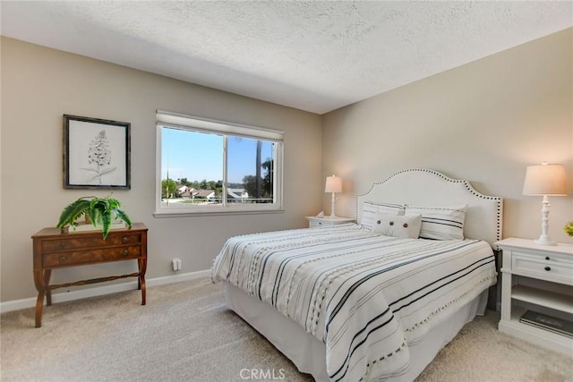 bedroom featuring a textured ceiling, baseboards, and light carpet