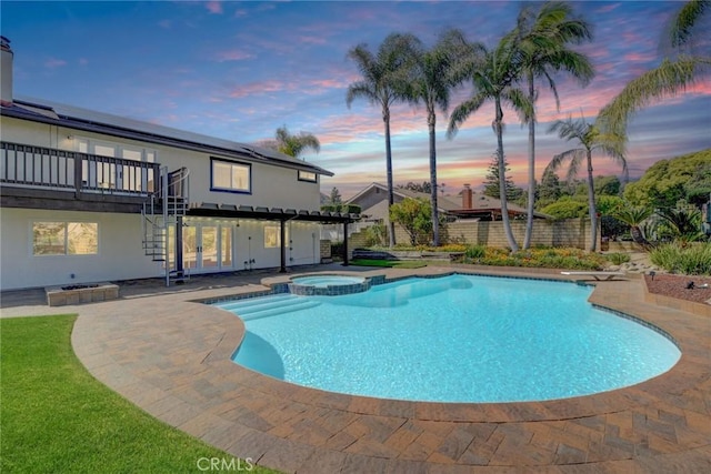 view of swimming pool featuring a wooden deck, stairs, a pool with connected hot tub, and a patio area