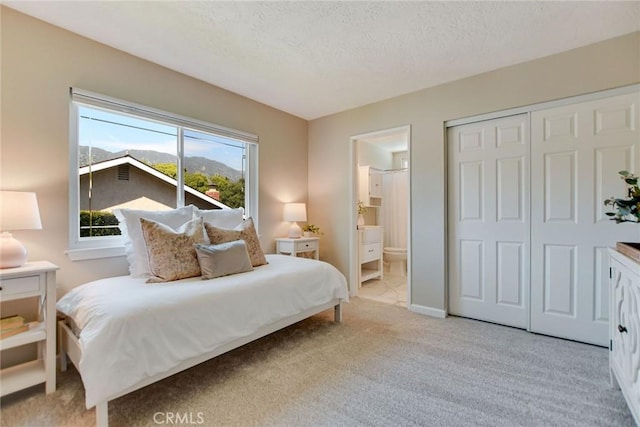 carpeted bedroom featuring a closet, connected bathroom, and a textured ceiling