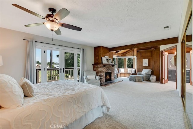 bedroom featuring carpet flooring, a fireplace, a textured ceiling, access to exterior, and french doors