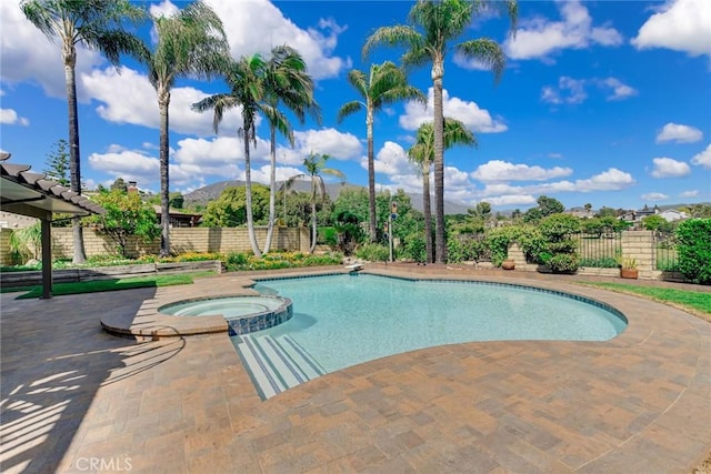 view of pool featuring a mountain view, fence, and a pool with connected hot tub