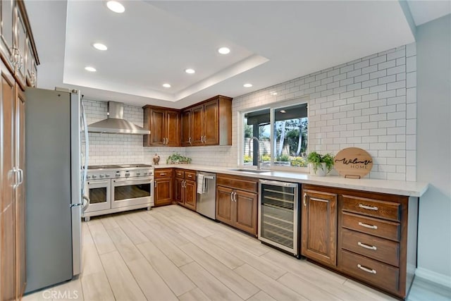 kitchen featuring appliances with stainless steel finishes, a sink, beverage cooler, recessed lighting, and wall chimney exhaust hood