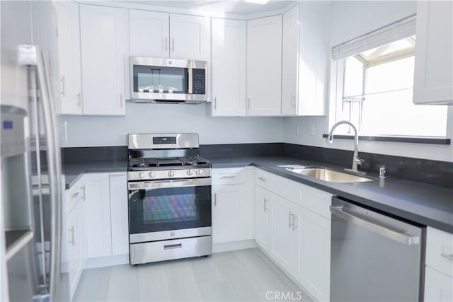kitchen with a sink, white cabinetry, appliances with stainless steel finishes, and dark countertops