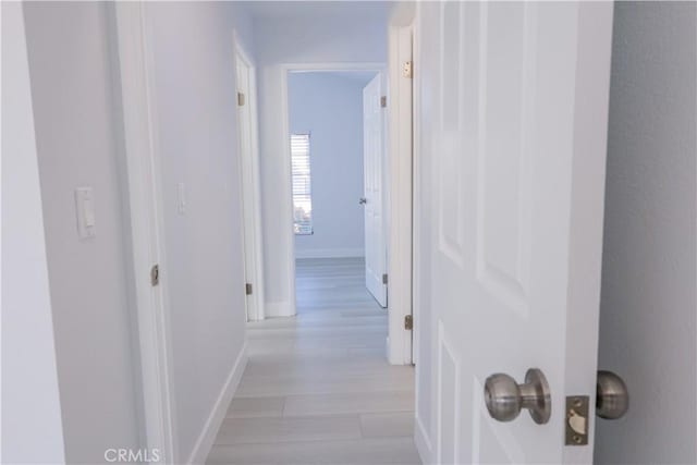 hall featuring baseboards and light wood-style flooring