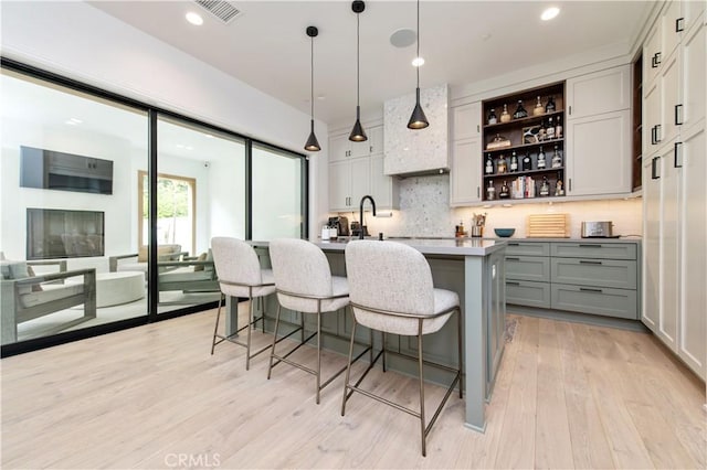 13 Goldenrod, Lake Forest, CA 92630 - bar area featuring tasteful backsplash, light wood-style floors, pendant lighting, and custom range hood