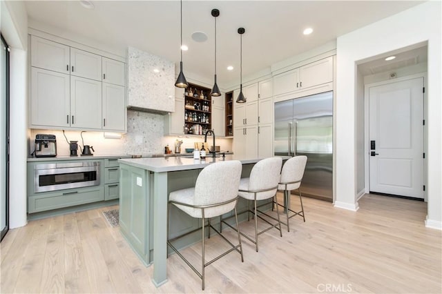 13 Goldenrod, Lake Forest, CA 92630 - kitchen featuring built in fridge, tasteful backsplash, light wood-style flooring, an island with sink, and recessed lighting
