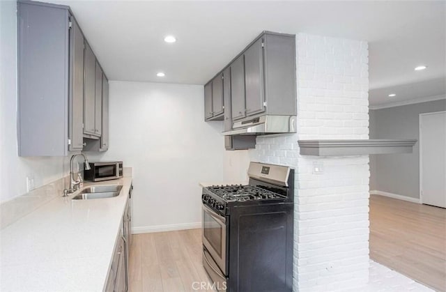 8641 Glenoaks Blvd Unit 107, Sun Valley, CA 91352 - kitchen with under cabinet range hood, a sink, light wood-style flooring, appliances with stainless steel finishes, and gray cabinetry