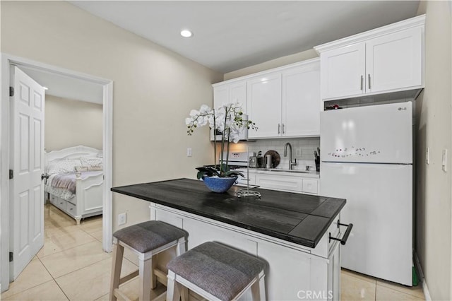 4250 Louise Ave, Encino, CA 91316 - kitchen featuring freestanding refrigerator, white cabinetry, light tile patterned floors, and backsplash