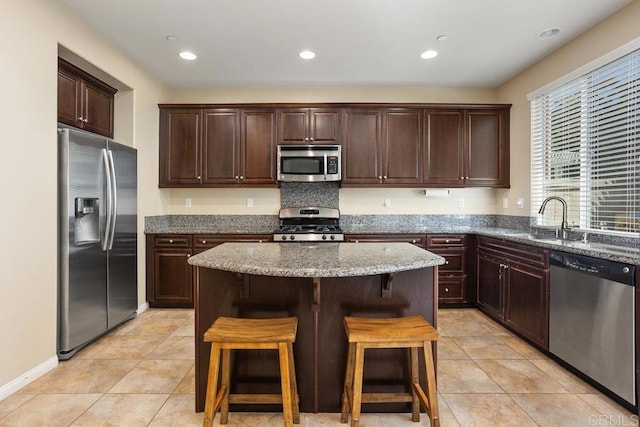 750 Arbor Glen Ln, Vista, CA 92081 - kitchen featuring dark brown cabinetry, appliances with stainless steel finishes, a sink, light stone counters, and a breakfast bar