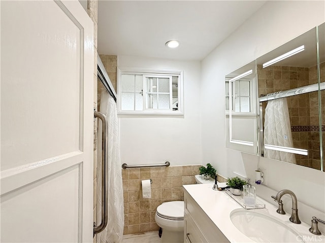 full bathroom with toilet, a shower with door, tile walls, and vanity