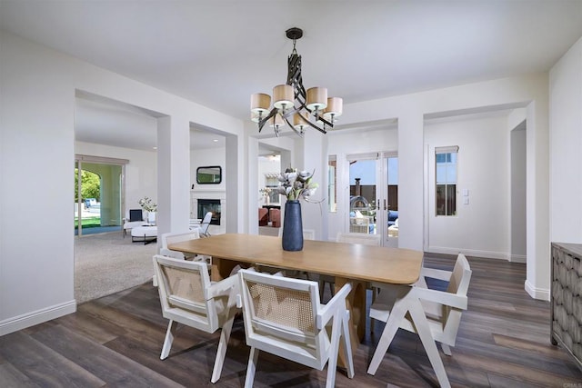 6981 Corte Langosta, Carlsbad, CA 92009 - dining space featuring a chandelier, a fireplace, dark wood-type flooring, and baseboards