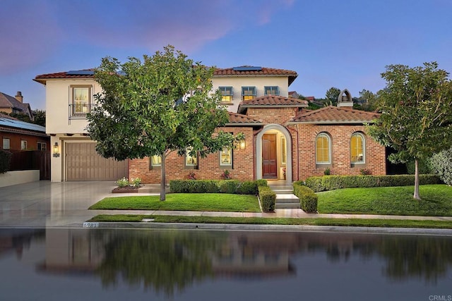 6981 Corte Langosta, Carlsbad, CA 92009 - mediterranean / spanish home featuring a garage, solar panels, driveway, a tile roof, and a yard