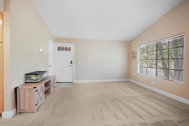 interior space featuring baseboards, light colored carpet, and lofted ceiling