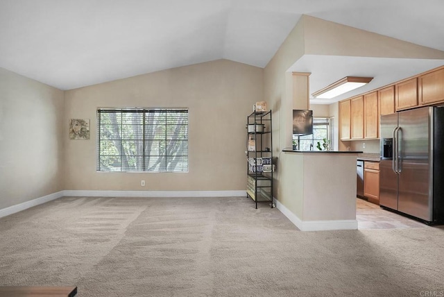 kitchen with baseboards, appliances with stainless steel finishes, vaulted ceiling, and light carpet